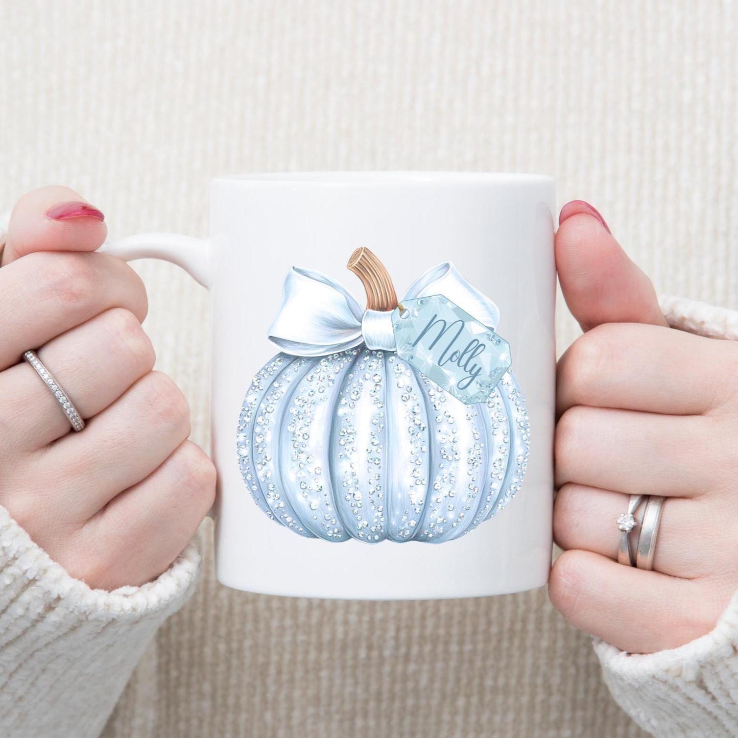 White mug with a blue pumpkin design and 'Molly' text, held by two hands.