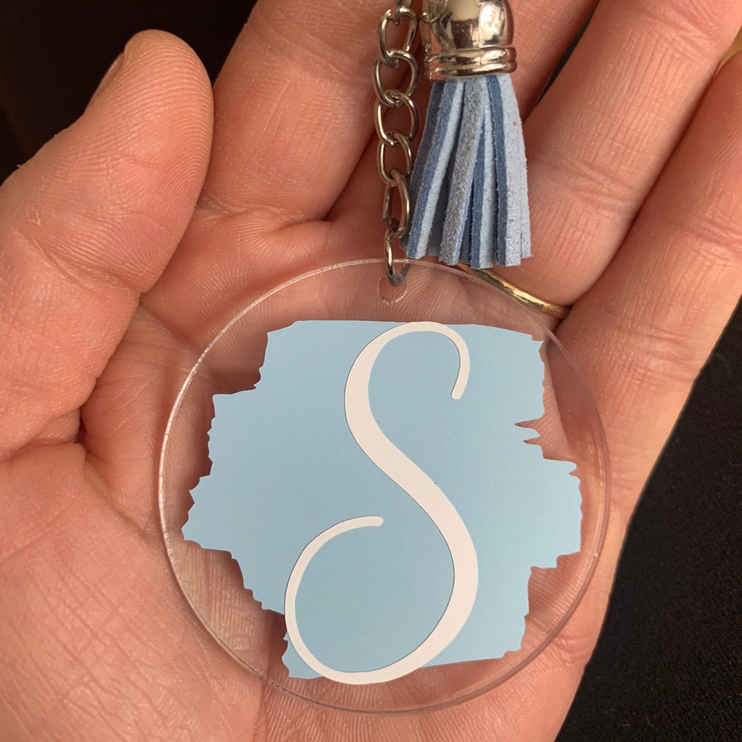 Keychain with a blue 'S' design held in a hand