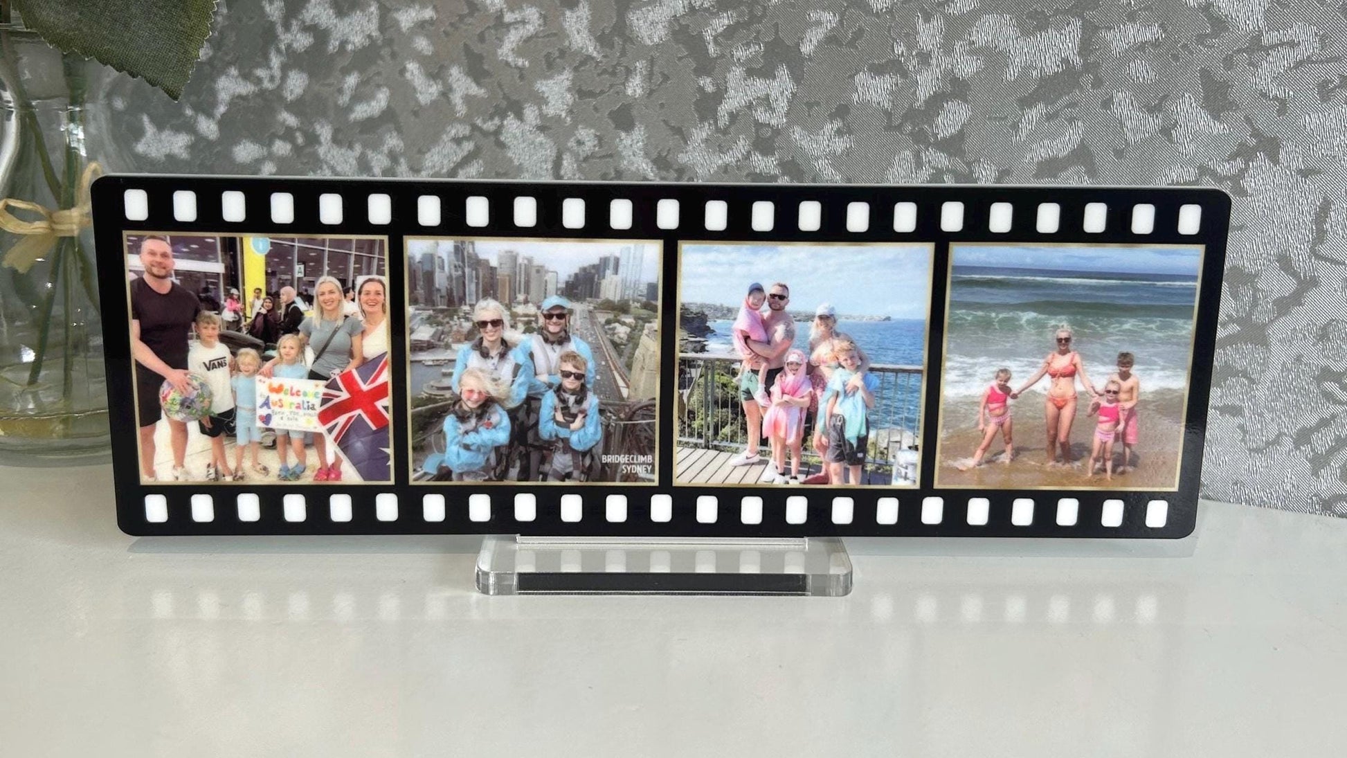 Film strip photo display with family photos against a textured wall.
