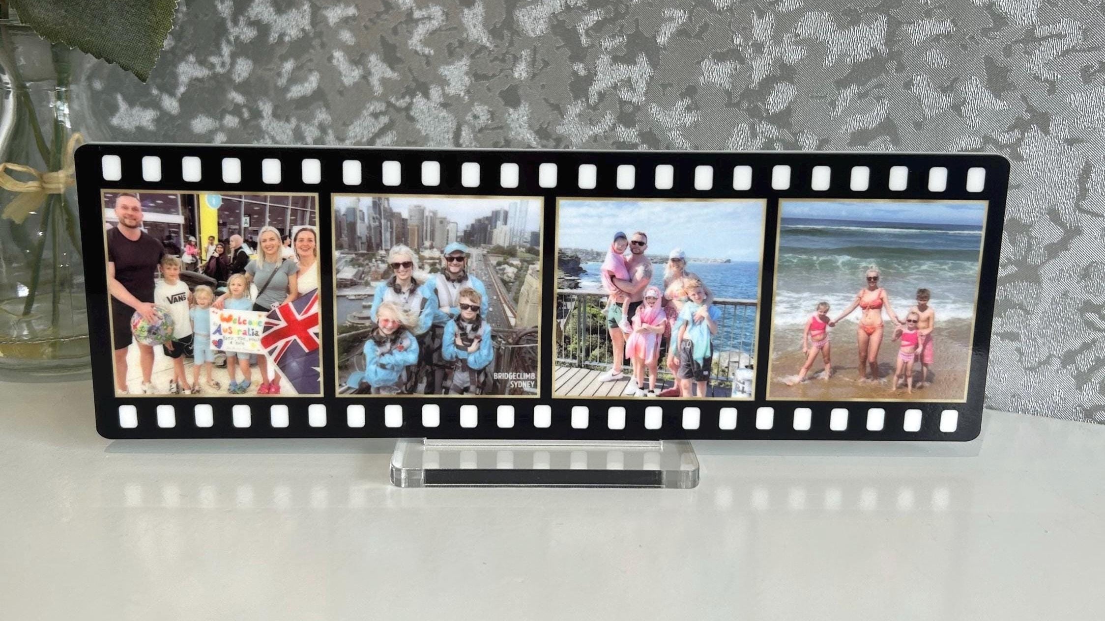 Film strip photo display with family photos against a textured wall.