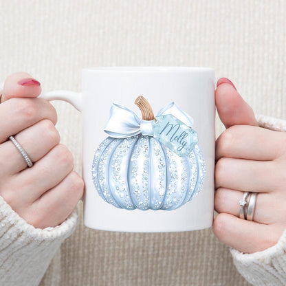 White mug with a blue pumpkin design and 'Molly' text, held by two hands.